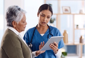 Nurse explaining information to an elderly woman using a tablet.