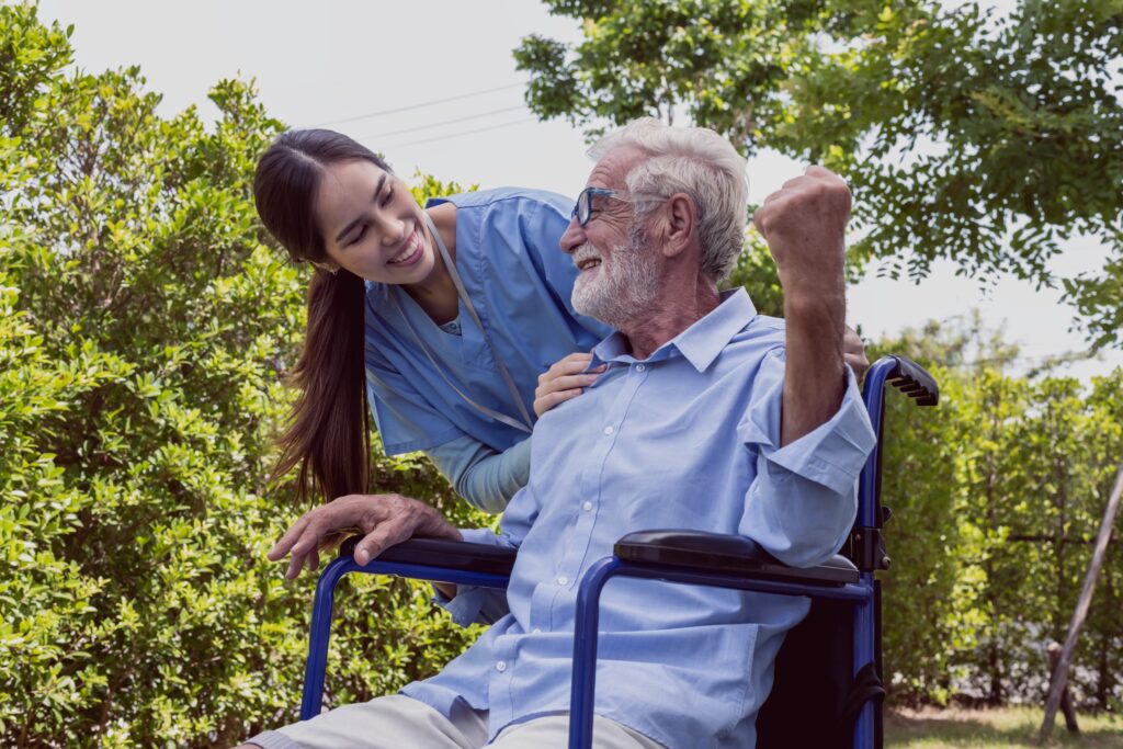 Friendly woman care taker with old man in wheelchair