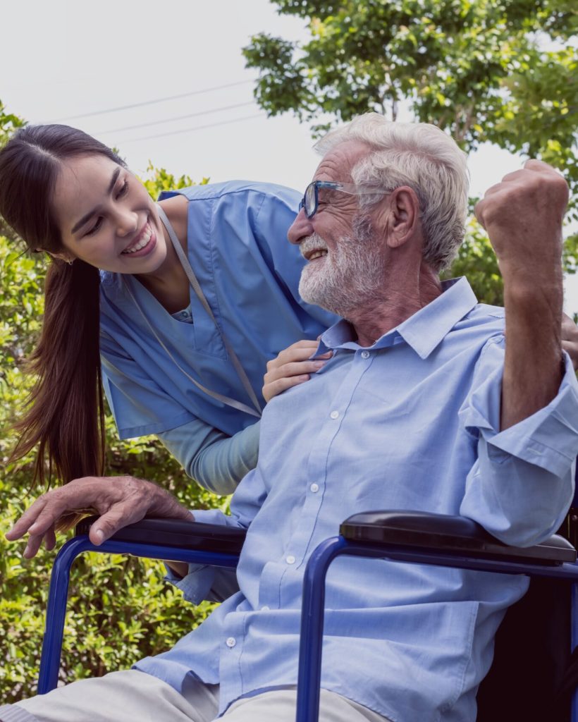 Friendly woman care taker with old man in wheelchair