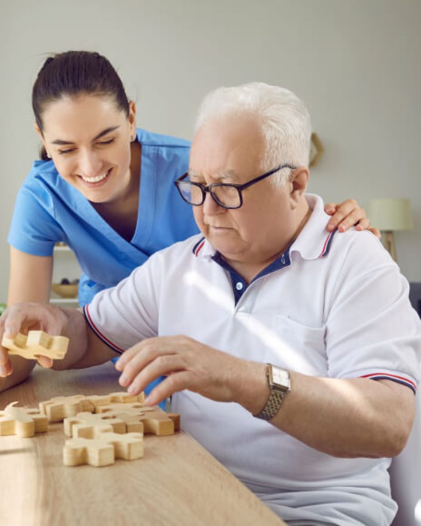 Nurse helping an elderly man with a puzzle.