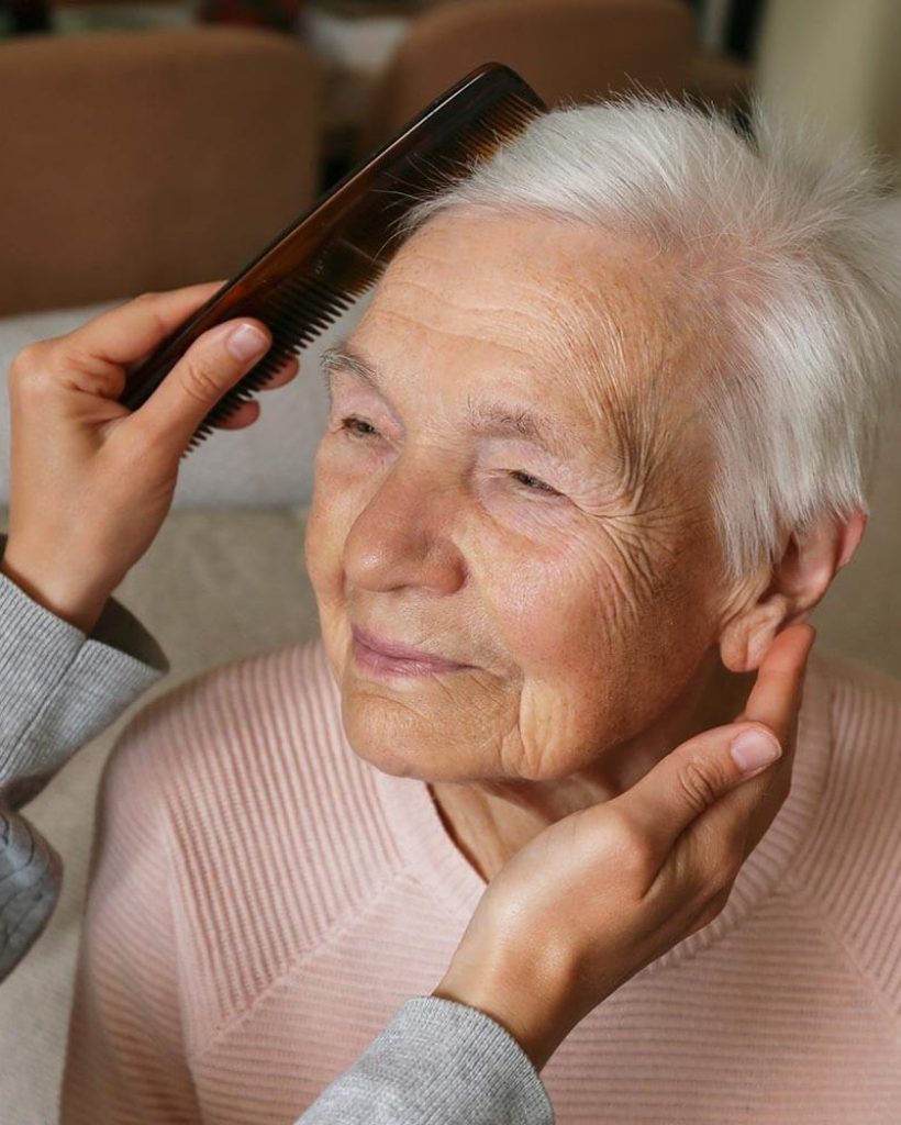 Elderly woman having her hair brushed